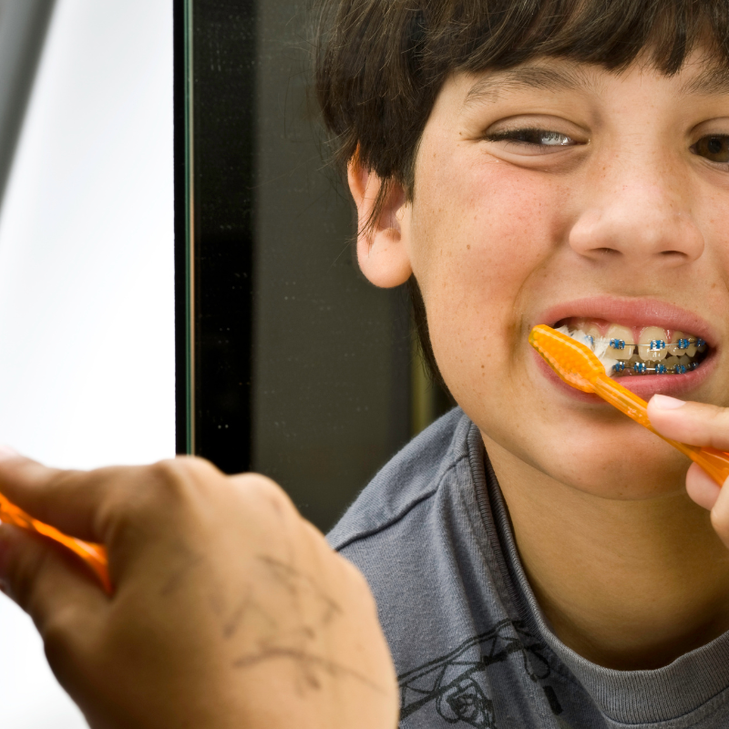Photo of kid with metal braces brushing teeth
