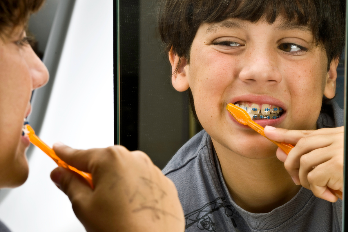 Photo of kid with metal braces brushing teeth